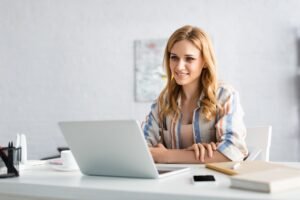 Selective focus of attractive freelancer working with laptop